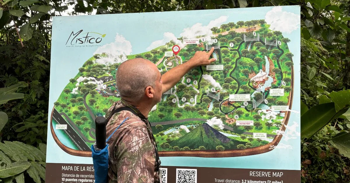Guide in Mistico Hanging Bridges Park Costa Rica is explaining hike path using a large bill board map.