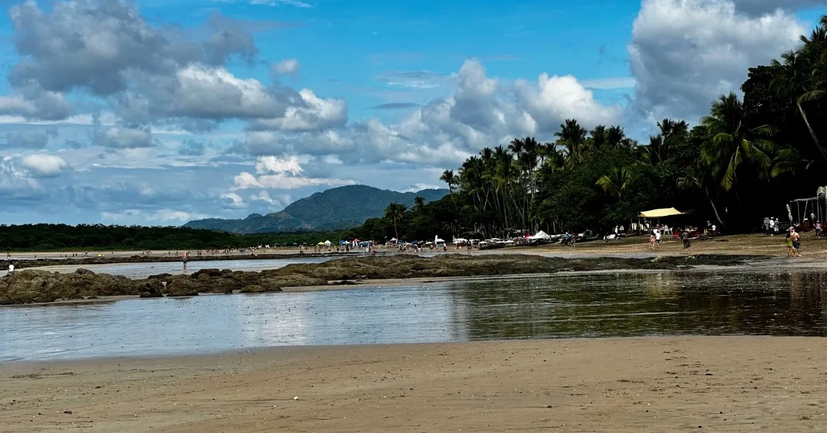 Tamarindo Beach, Guanacaste with rocks amongst the sandy beach. People are enjoying the beach activities.