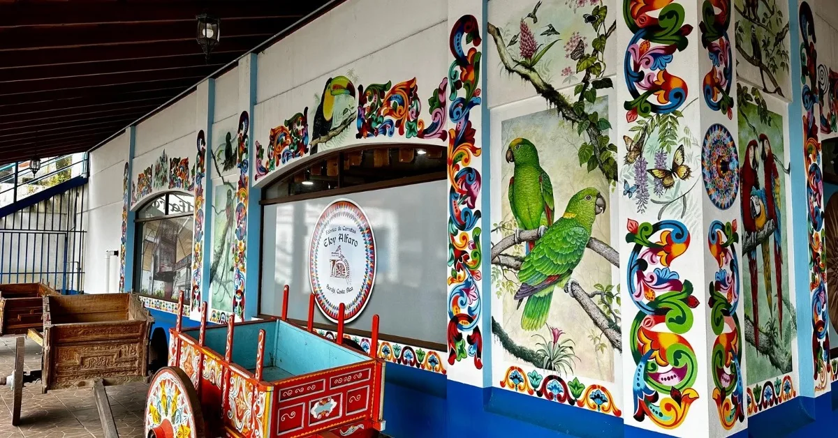 Entrance to Sarchi crafts workshop and retail shop has painted walls with flowers, parrots and butterflies. In front are original o charts used to transport coffee and other goods in Costa Rica.