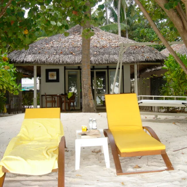 Two yellow sun loungers outside a beach bungalow on the Madives. This is another one of our dreamy destinations for romantic getaways.