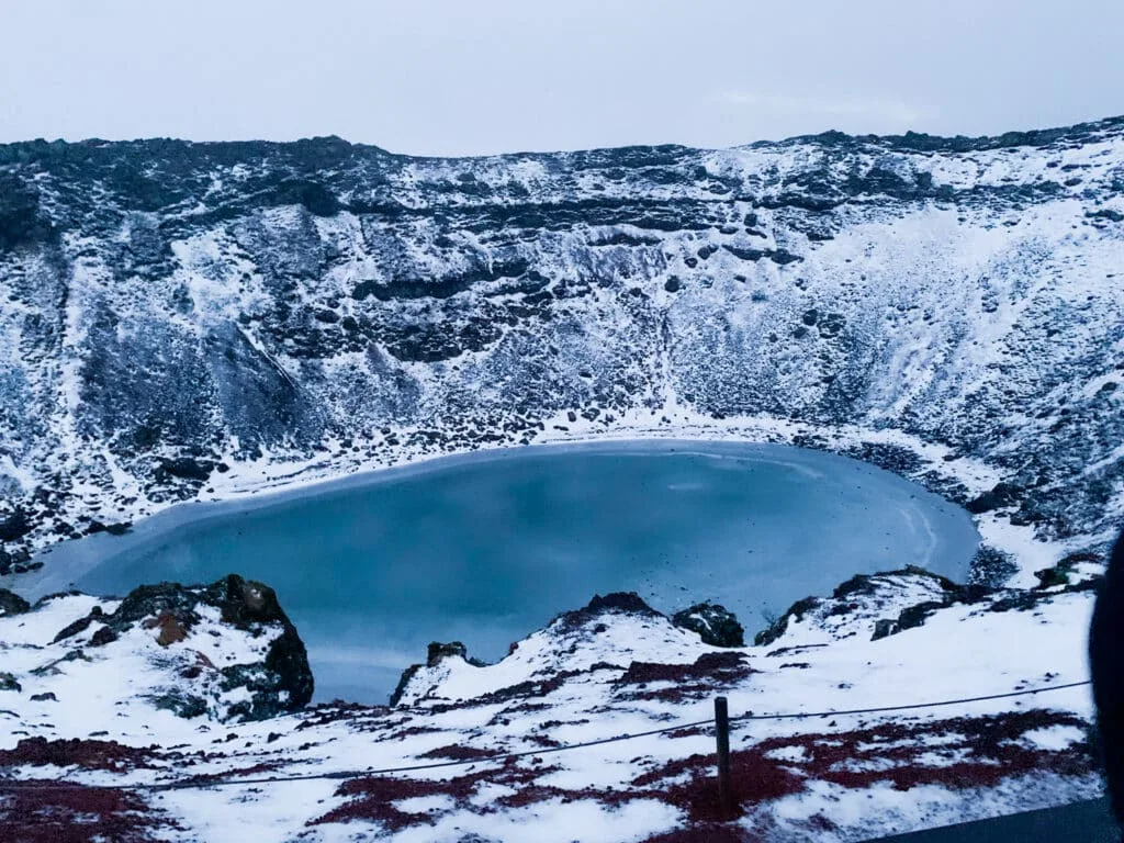 Iceland Golden Circle's Kerid Lake Crater in winter with azure blue frozen water.