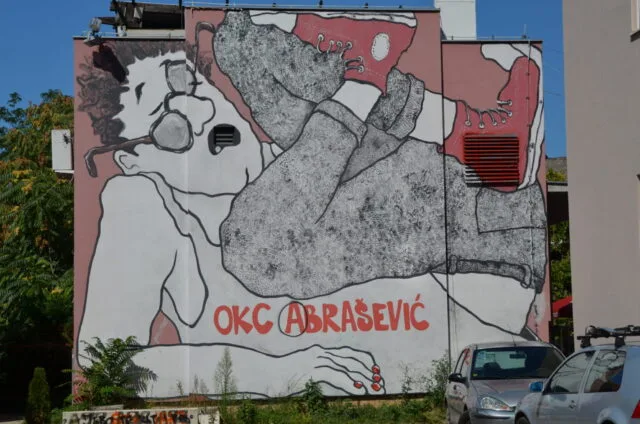 Grafitti on a building in Mostar depicts a person lying with their feet up in the air in a panicked look.