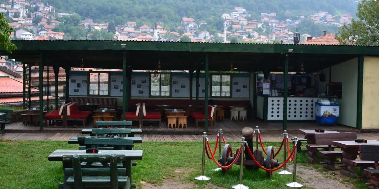 A restaurant in Sarajevo with partially covered seating and grassy area for visitors.