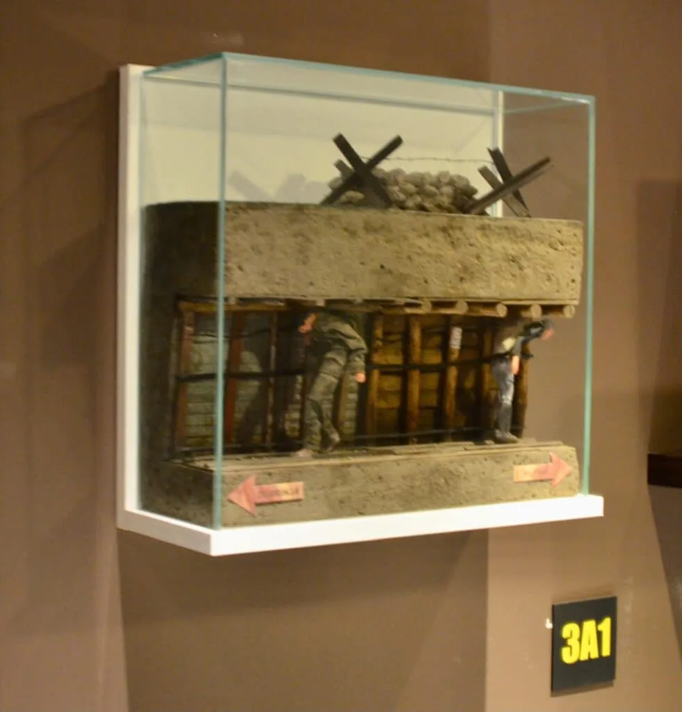 A glass box attached to a wall contains a miniature of the Tunnel of Hope in Sarajevo