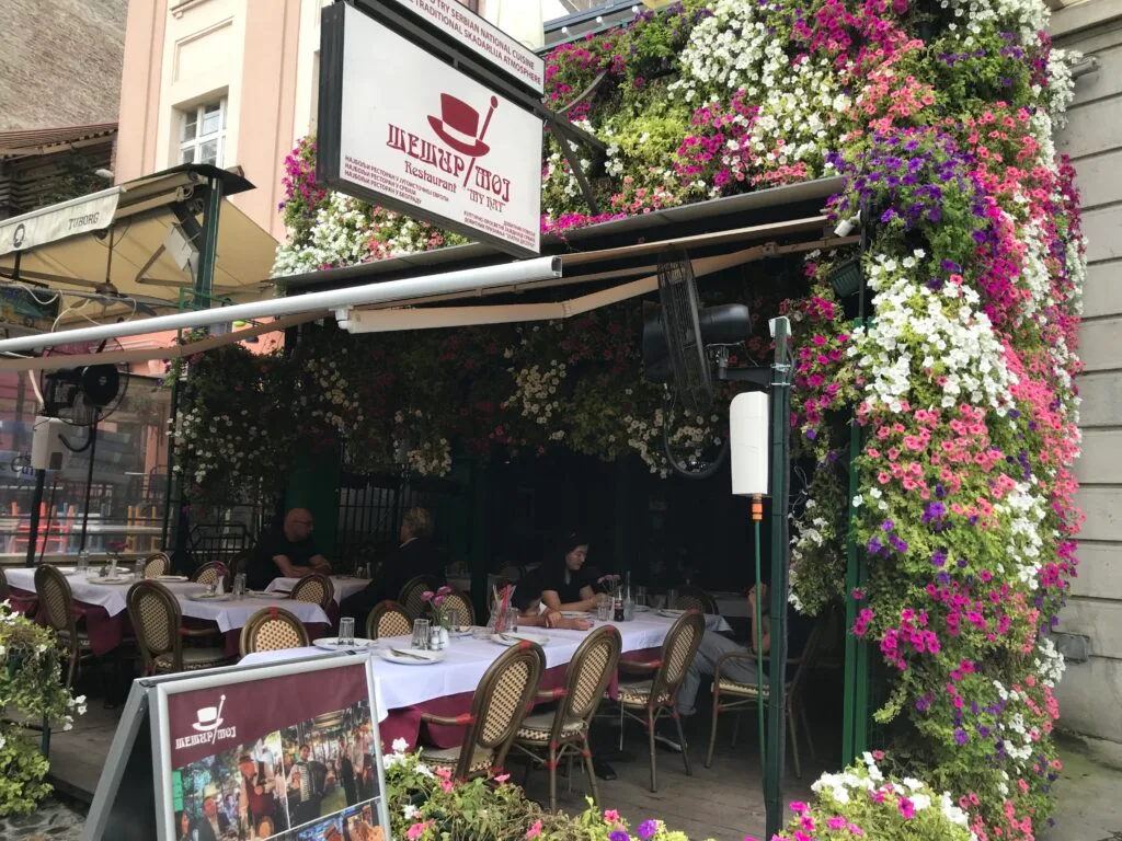 Hanging baskets of flowers surround the entrance to a restaurant in Sarajevo.