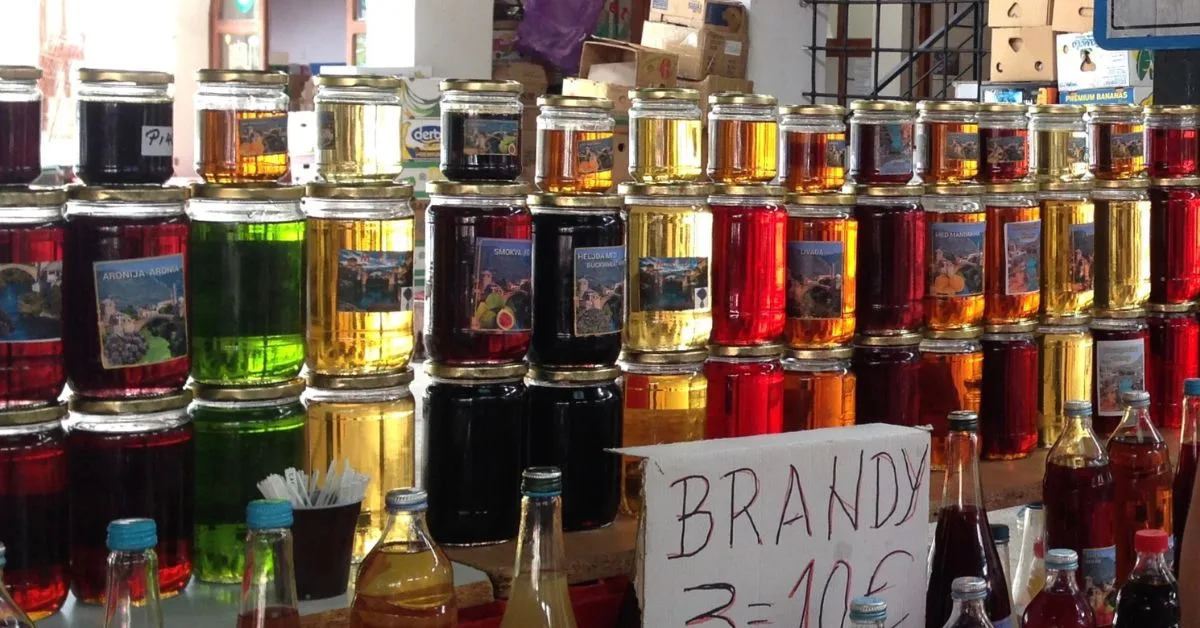 Rakija market stall in Sarajevo displaying jam jars full of home-made brandy.