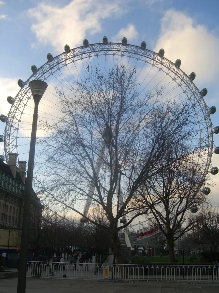 A ferris wheel known as the London Eye with multiple cabins for passengers to see the skyline of London as it rotates slowly.