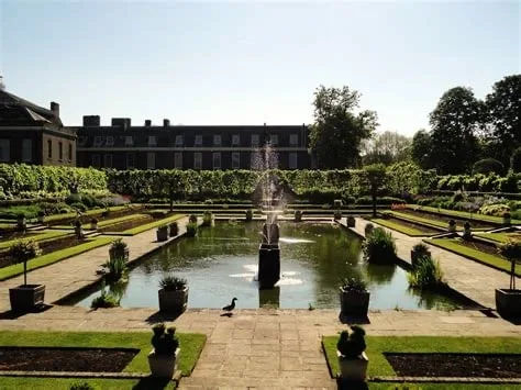 Kensington Gardens in central London with a large pool surrounded by shrubs.
