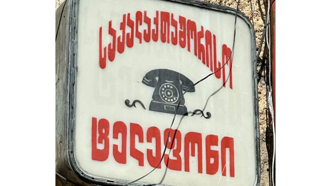 A street sign in Georgian Alphabet with a phone icon.