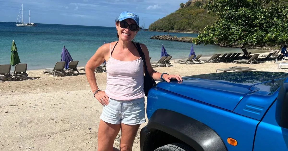 Woman on a beach standing next to a blue car