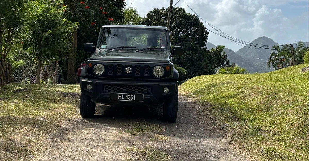 Jeep Parked up on a track road which is unpaved. Hills in the background. Grassy banks either side of the vehicle.