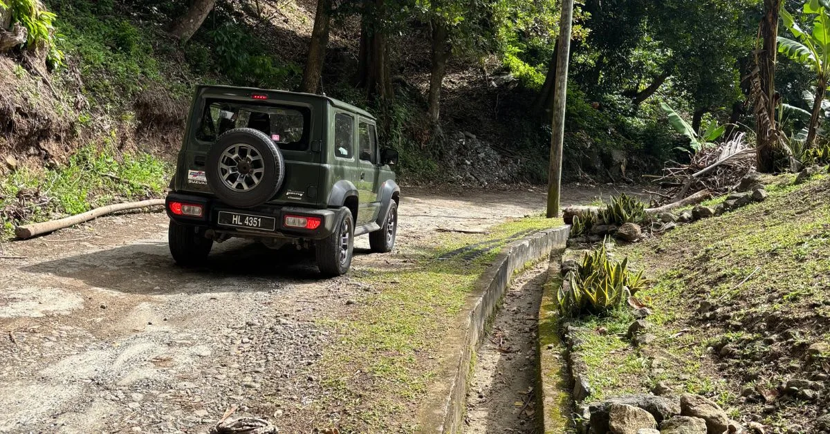 Jeep parked showing condition of road which is unpaved and with a large gully to the right of the vehicle.