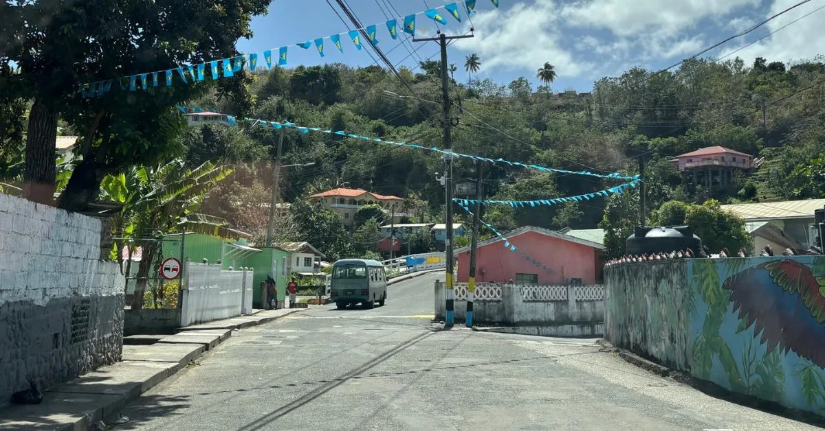 Pretty village in St Lucia with blue bunting flags and picture of a bus driving over a bridge