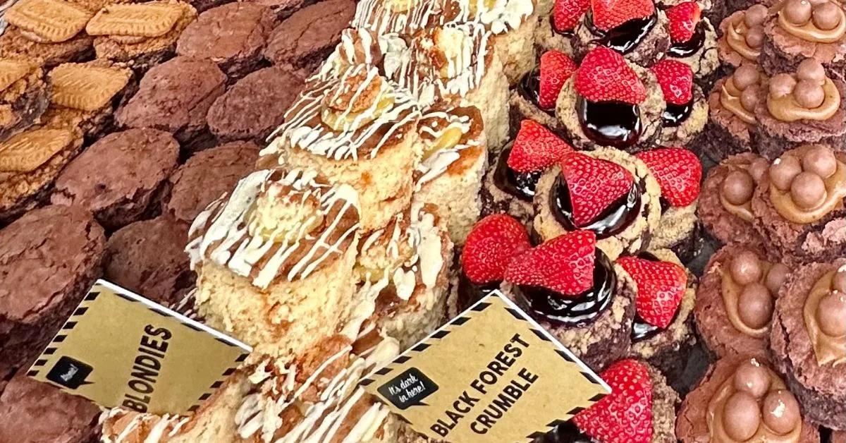 Rows of home made cakes on show with topping including chocolate and strawberries.