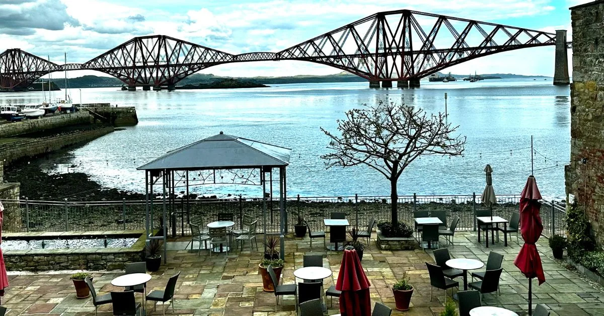 The 3 red steel spans of an UNESCO rail bridge across Firth of Forth in Edinburgh from a cafe terrace.