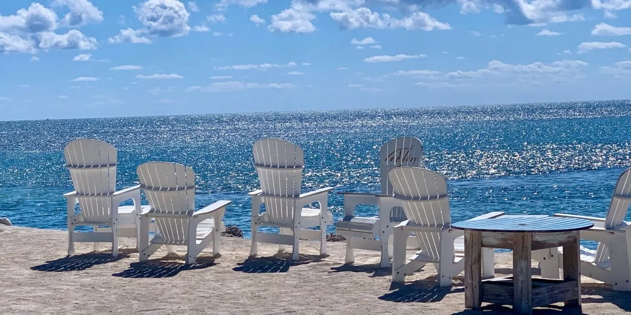 White chairs on a quiet beach with gentle waters lapping the sands.