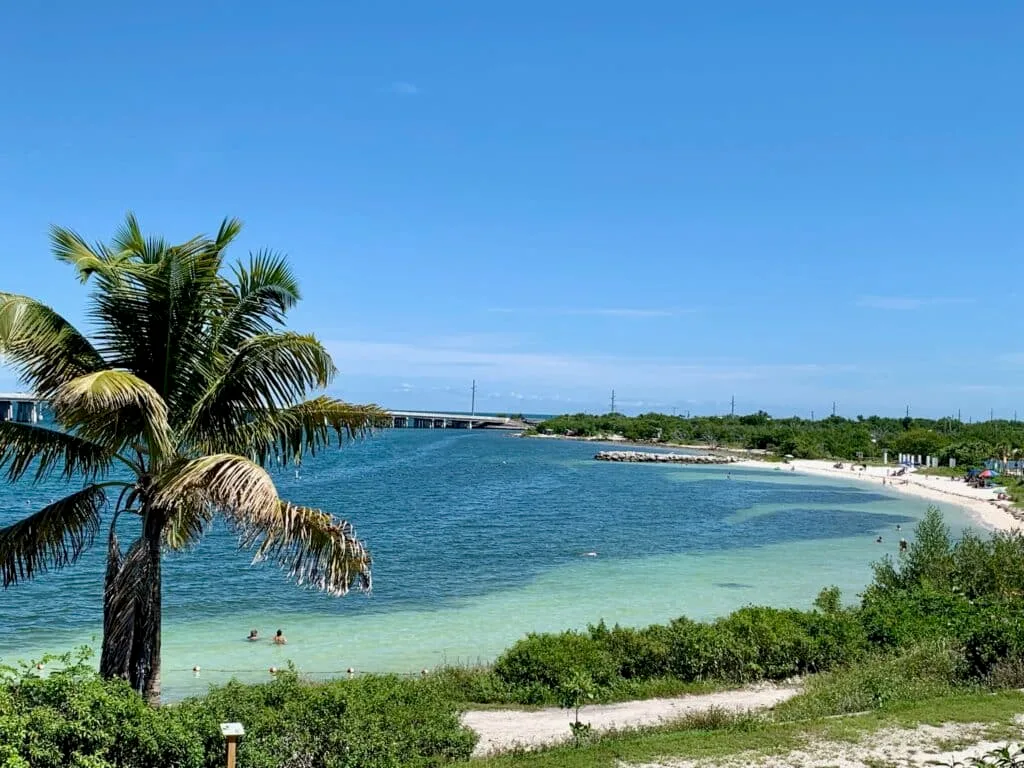 Curved bay with shallow blue waters and sandy beach.