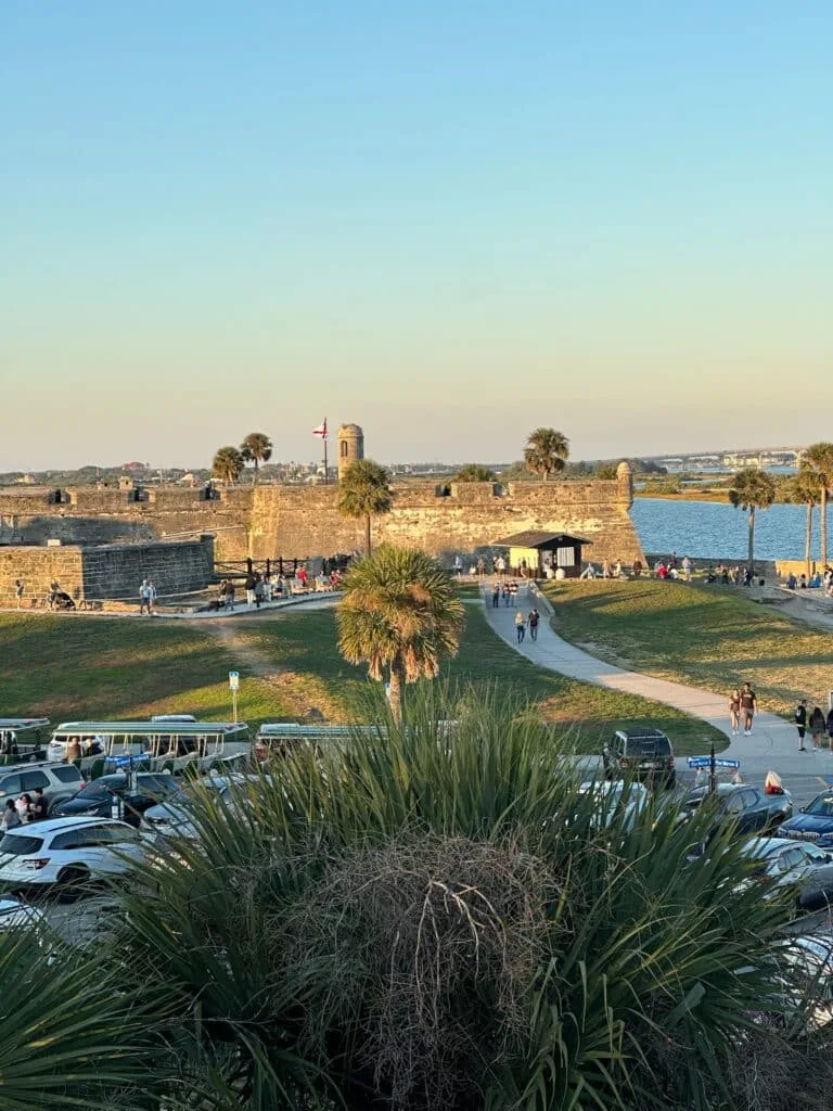 A stone fort with lookout tour that people are walking around to visit. Located next to a bay.