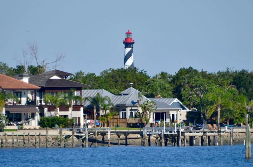 A lighthouse with red light beacon and black and white stripped tower.