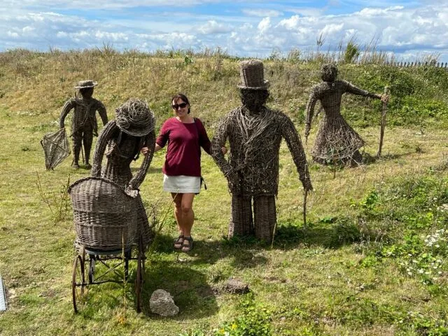 Tourist is standing in a field which is part of a museum in Suffolk. Figures made of wicker represent Victorian Era life in England.