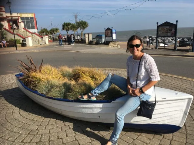 Women sitting on a boat now used as a flower pot.