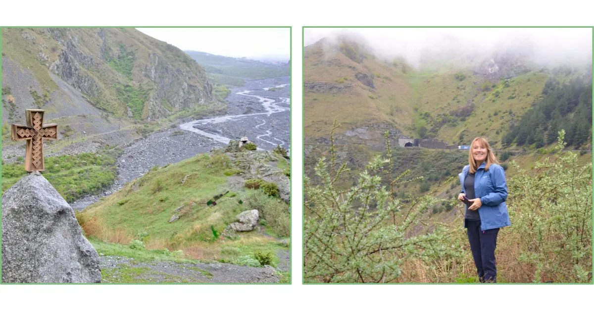 View of a deep gorge with a Georgian Cross on a stone at the top of a road crossing the gorge.