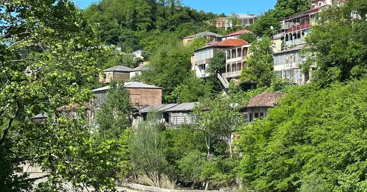 Ancient multi-story homes with ornate balconies are built up from the Rioni River in Kutaisi Georgia. They cling to the hillside.