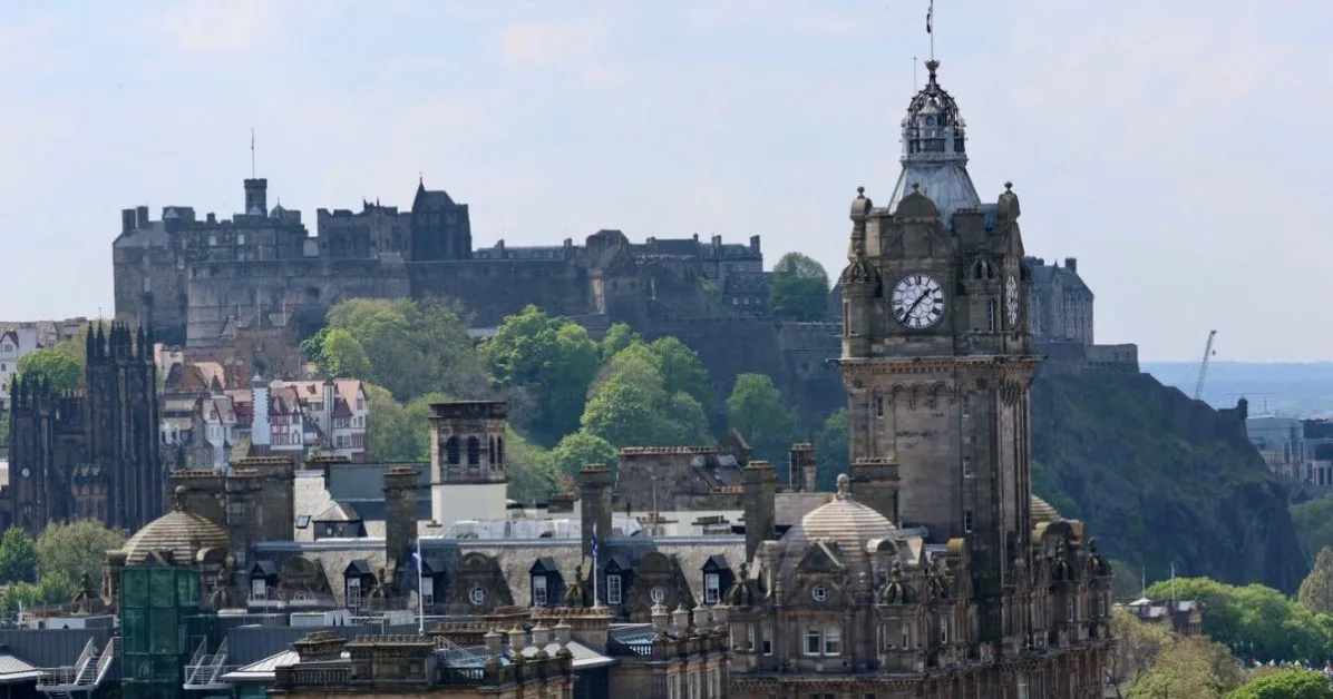 View of Edinburgh Castle on a volcanic rock and the tower of Balmoral Hotel with its famous city clock.