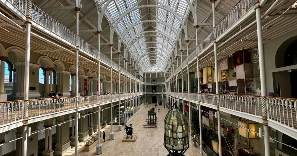 3 level balcony inside the National Museum of Scotland which is in Edinburgh. Ornate railings and open floor areas with exhibits create a beautiful setting.