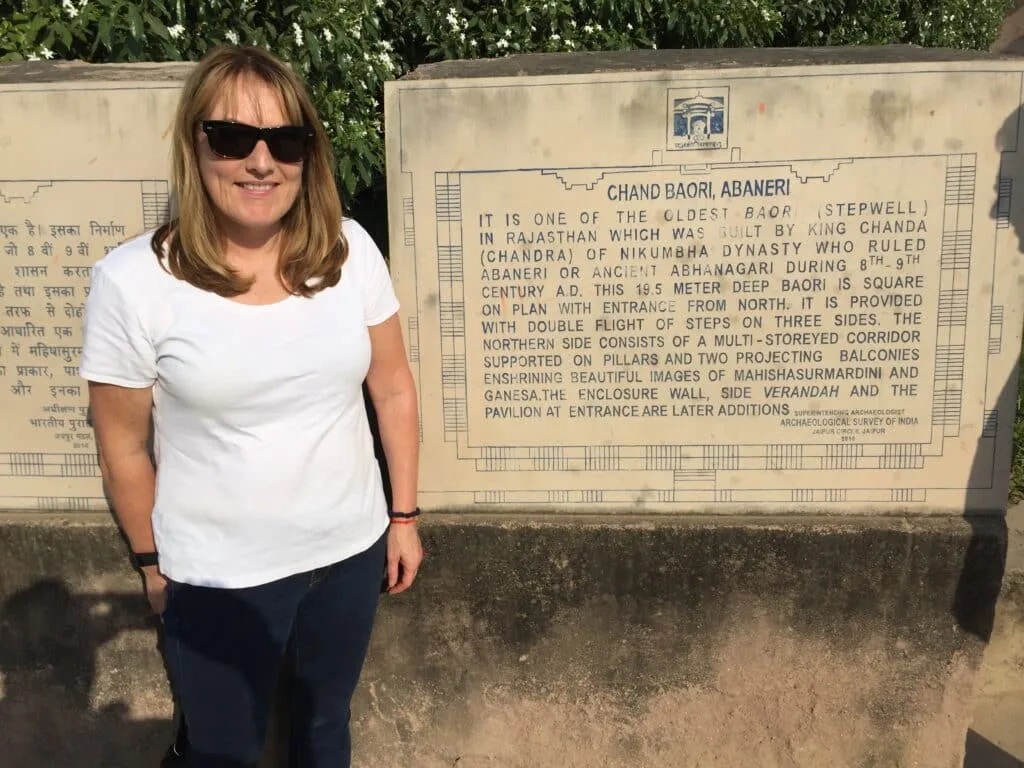 Woman standing next to an entrance map of an ancient Indian well system.