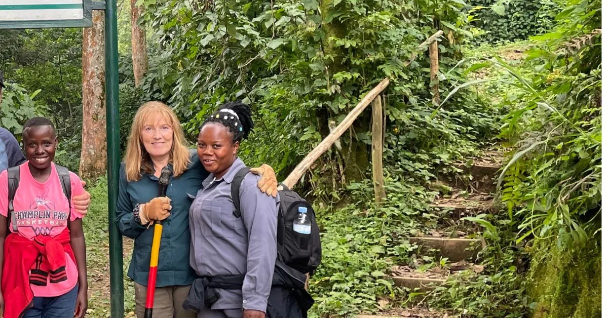 2 Porters with a trekker stand at the start of the forest area in bwindi Uganda.