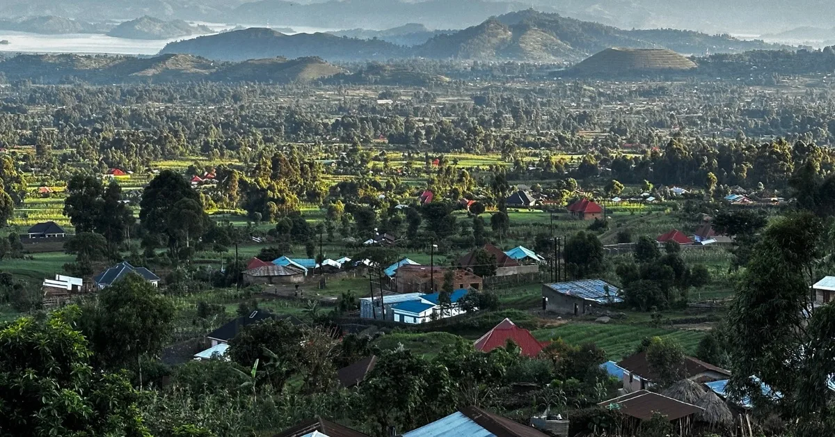 Views of valley dotted with rural homes  below Mt Muhabura where Mgahinga Gorilla family live. Volcanic Mountains and a lake can be seen in the stance.