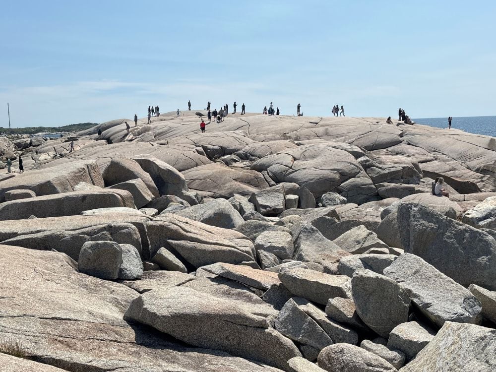 Visitors walking across the smooth granite slabs at Peggy's Cove