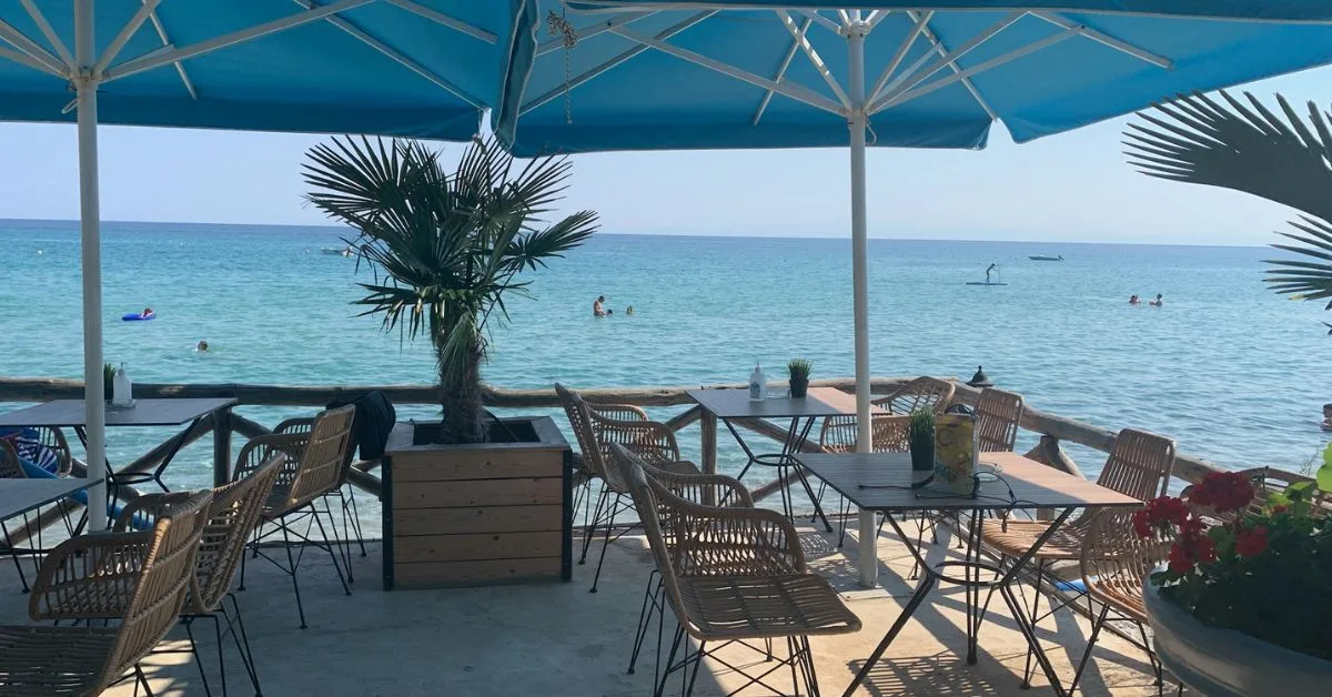 Cafe style casual dining . Table and chairs under canopy overlooking sea and beach
