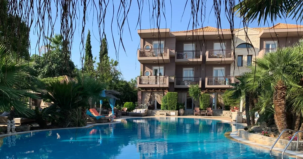 Small Hotel with a kidney shaped pool in front and shrubbery to the side