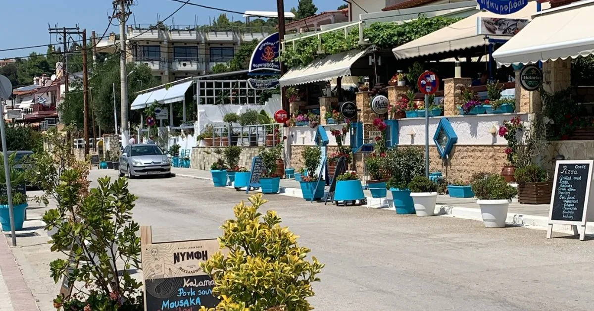 Road in front of the beach shows casual taverna type restaurants
