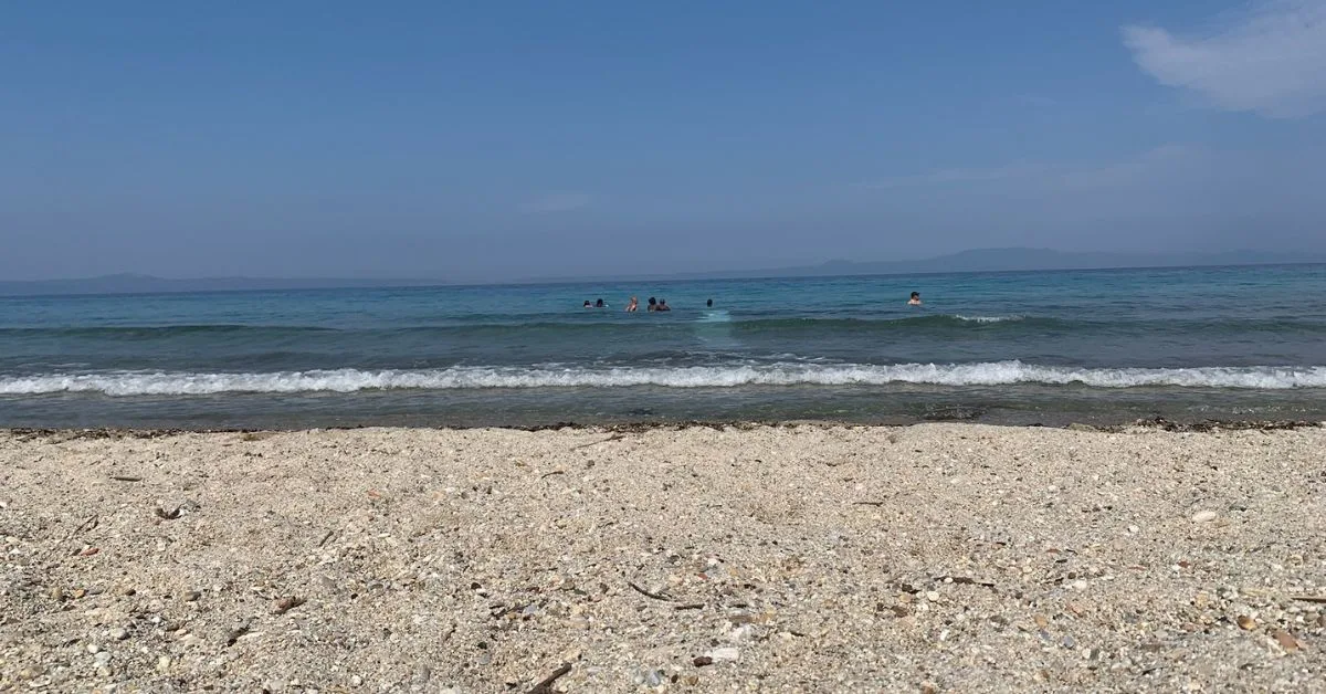 Quiet shingle beach with a few people in the sea