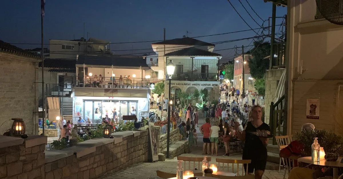 Night time in Afytos shows people eating in pavement restaurants and shopping and pottering around the narrow streets