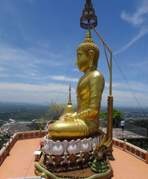 A gold seated Buddha statue sits atop a building