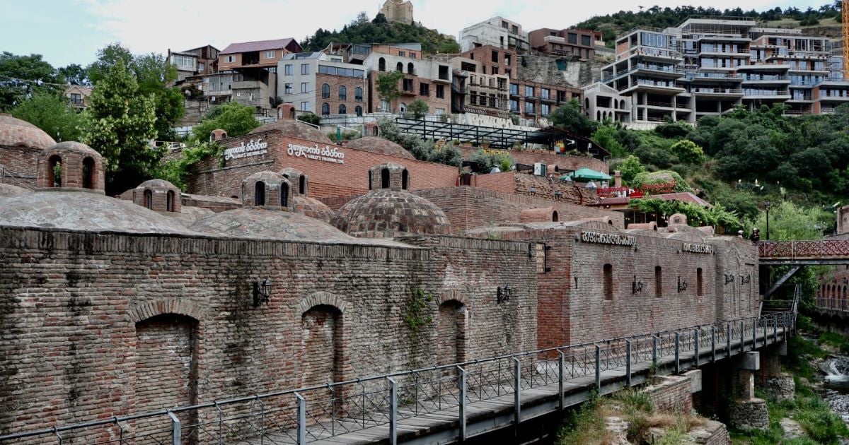 Aerial view of Tbilisi's historic rooftops with red and tin roofs in a vibrant cityscape