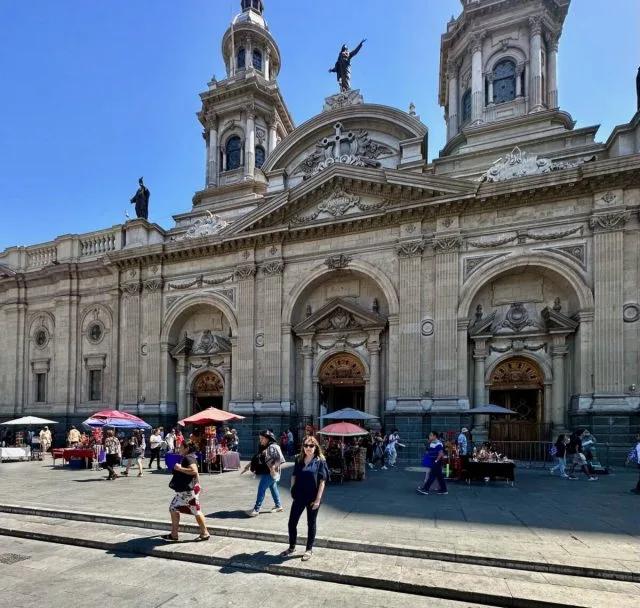 Travel blogger Jude in front of Cathedral Santiago Chile. Market stalls sell to visitors around the buildings main entrances.
