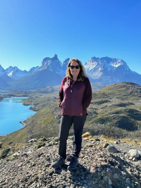 Woman standing on a mountain peak waiting for condor birds to fly near by. These birds nest on a ledge just below where she is standing,