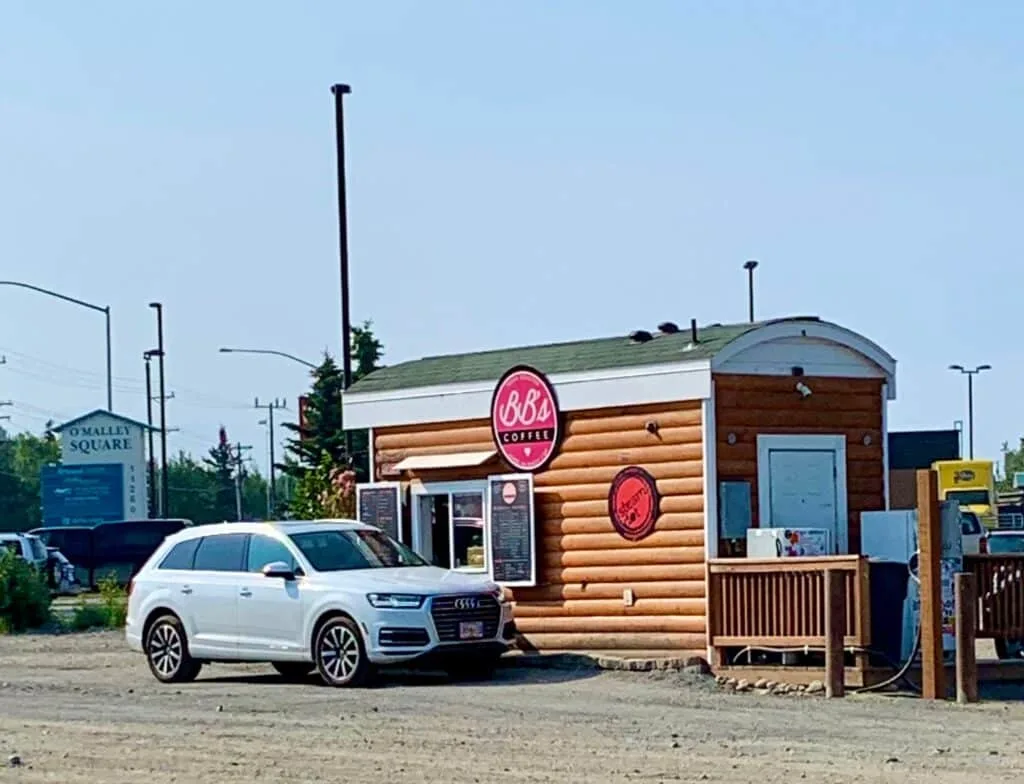 A car is stopped at a small wooden hut which operates a drive through coffee shop in Anchorage, Alaska.