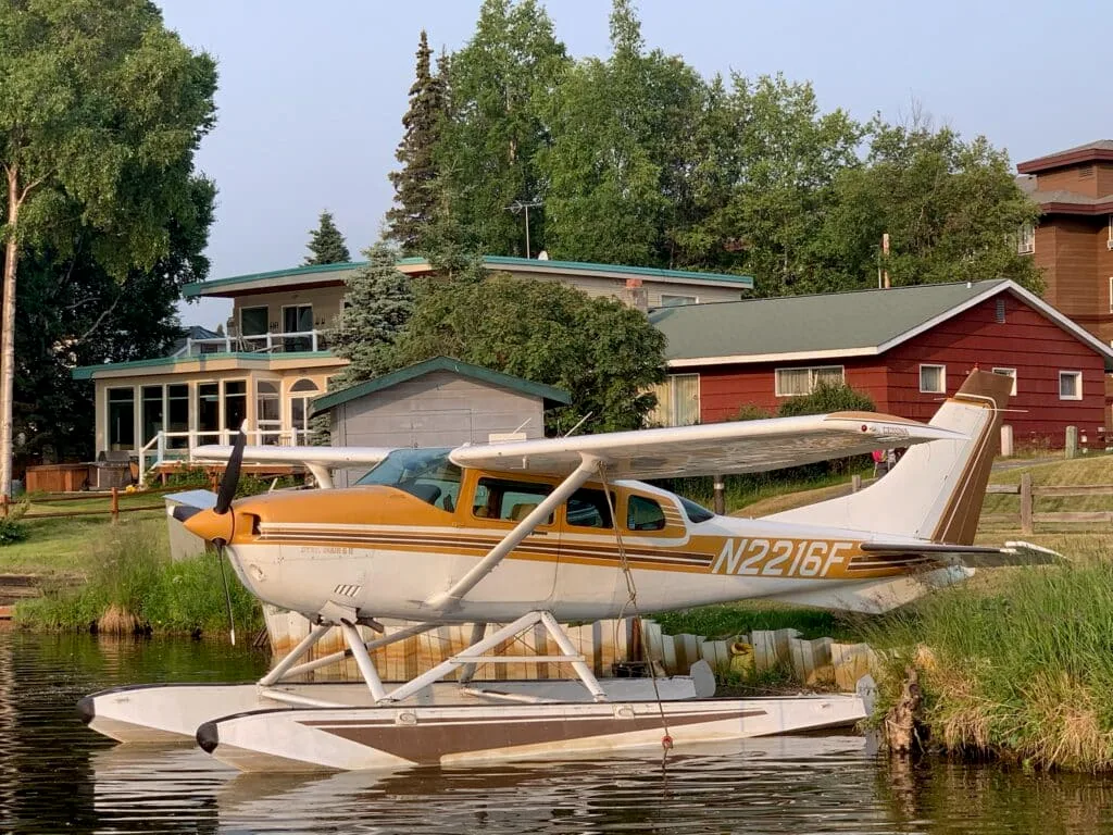 A float plane is parked on a lake next to a house in Anchorage, Alaska.