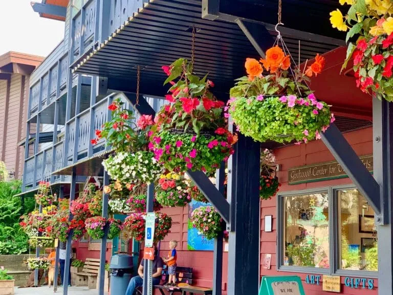 Baskets of flowers in bloom hang from the entry way of a cafe in Girdwood, Alaska.
