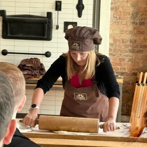 Woman rolling out dough in a bakery setting.