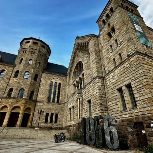 Entrance to the 1956 museum is shown in large numbers at the base of the tower of a palace.