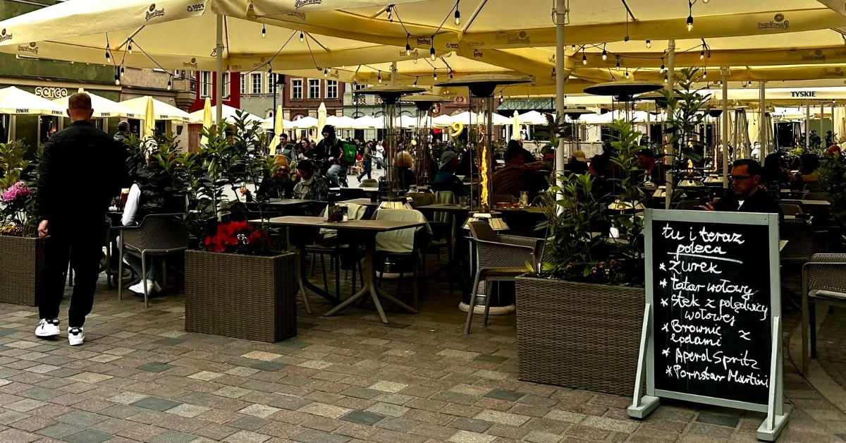 Outdoor dining in Poznan where people are sitting at tables around the main square.