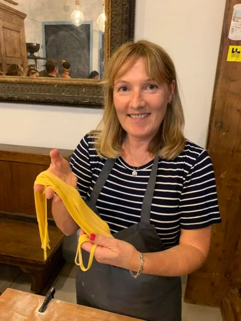 Woman making pasta in Florence Italy with strings of spaghetti.