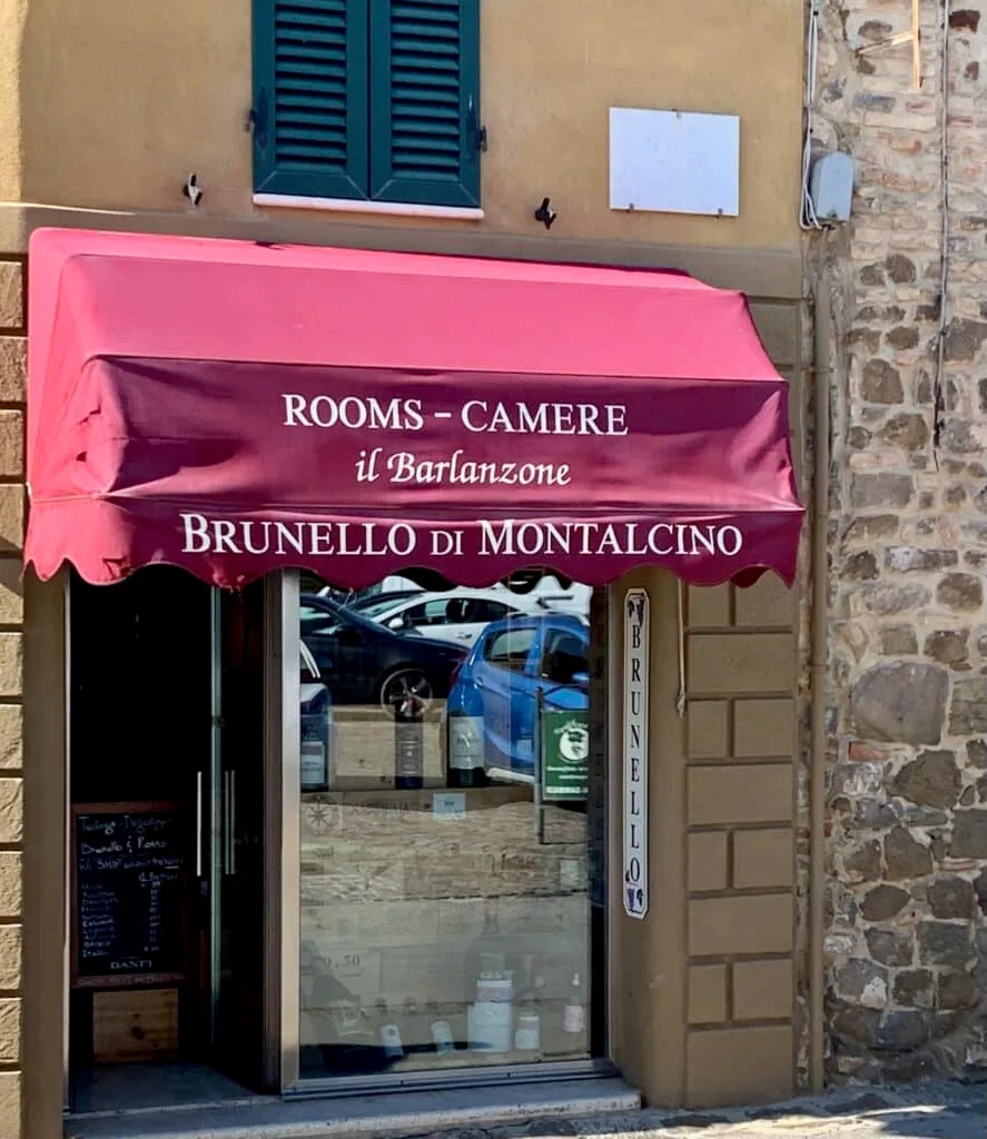A red awning advertises entrance to wine tastings at a small town in Tuscany.